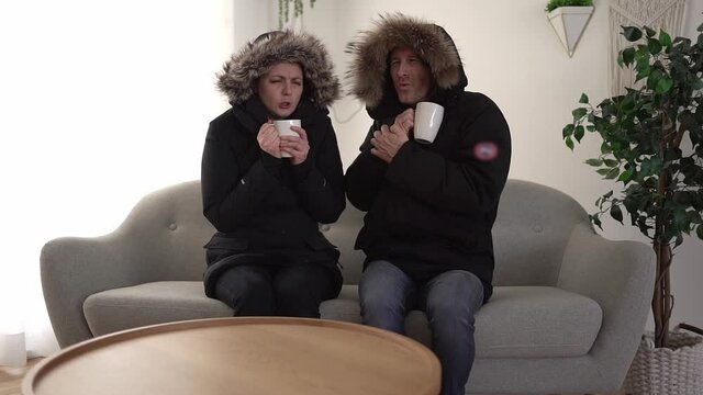 A Couple have cold on the sofa at home with winter coat