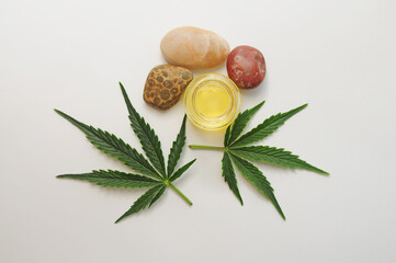 Marijuana leaves, cbd oil, sea stones, spa recreation. Fresh cannabis leaves close up, isolated on white background. Home relaxation, pastime therapy. Alternative medicine.