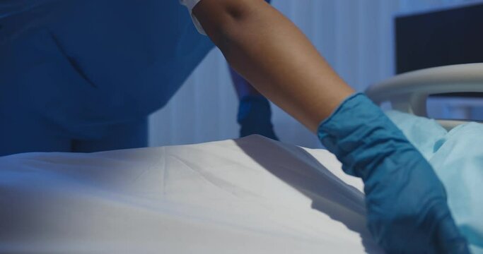 Close up of medical worker on gloves covering dead male patient with sheet