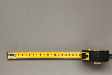 Construction yellow measuring tape on grey background. Trendy colors of 2021. - Powered by Adobe
