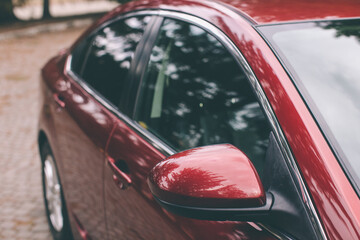 rear-view mirror and the door of the dark red sports car