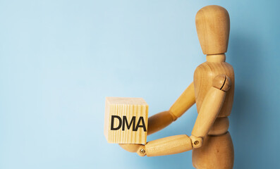 Wooden man holding a wooden cube with acronym DMA-DIRECT MARKET ACCESS. Business and finances concept.