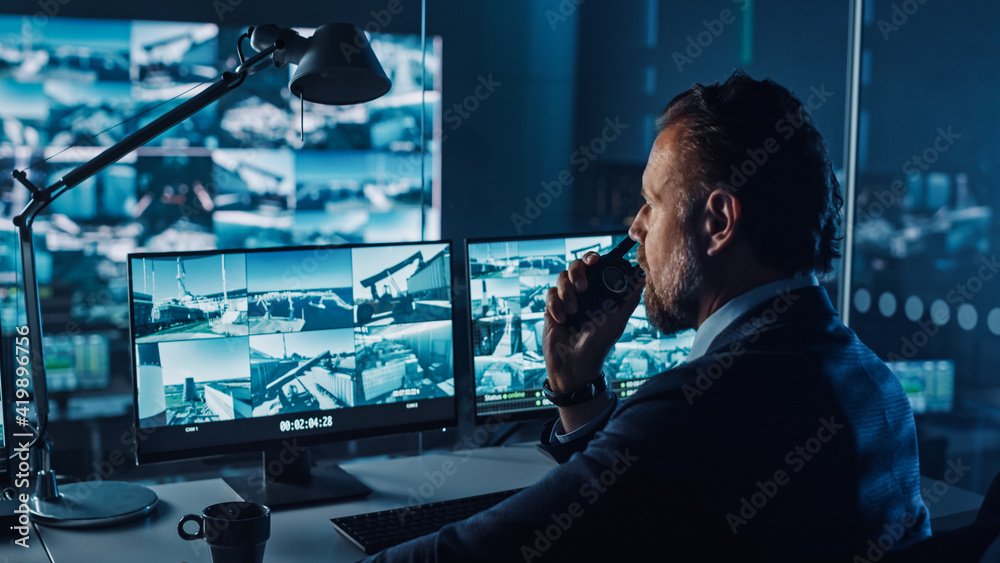 Leinwandbilder male officer works on a computer with surveillance cctv video in a harbour monitoring center with mu