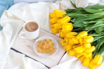 A bouquet of fresh yellow tulips and breakfast with coffee and homemade marmalade. Breakfast in bed. Spring flowers. The concept of spring and holiday, March 8, International Women's Day,