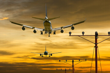 rear view of two airplanes for commercial passenger or cargo transportation aircraft flying in sequence and spread the wheel for landings to airport on golden sunset sky in dusk or evening