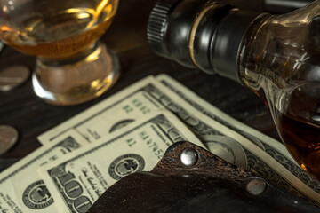 Stack of dollars, leather wallet and a bottle of whisky