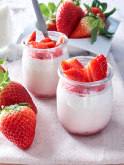 two natural yogurts with fresh strawberries on top, healthy eating concept