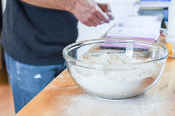 Person making bread in home kitchen adding ingredients to make the dough