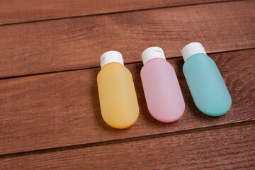 Set of pink, blue and yellow tubes with moisturizer cream or cleansing on wooden board. Beauty and spa concept.