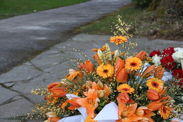 Trauerkranz mit Blumen in Orange nach Beerdigung auf dem Friedhof