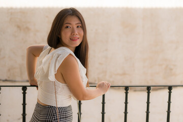 Asian woman as tourist in Andalusia Spain - young happy and beautiful Korean girl relaxed on street balcony enjoying holidays travel walking traditional downtown Seville