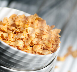 cornflakes are poured into a white plate close-up, scattered on the table