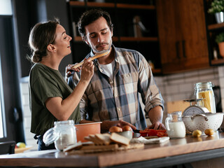 Husband and wife in kitchen. Young couple preparing delicious food at home.