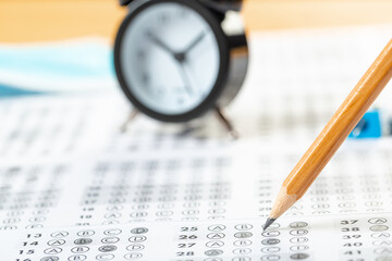 alarm clock, optical form of standardized school test with bubble and black pencil, answer sheet, education concept