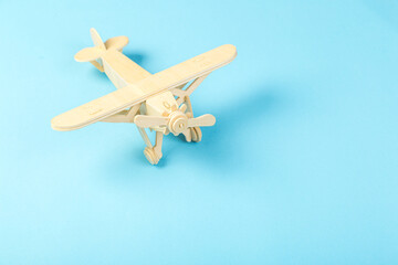 Model of a wooden toy plane, airliner, on a blue background. the concept of travel and transport and children's fantasies
