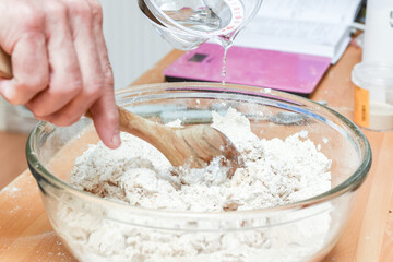 Person making bread in home kitchen adding ingredients to make the dough