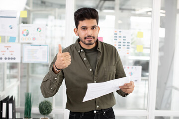 Handsome indian man showing thumb up at office