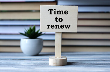 TIME TO RENEW - words on the information board against the background of a stack of books