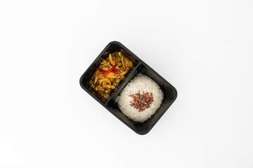 Top view of spicy curry pork with rice in side the black contain box isolate in white.