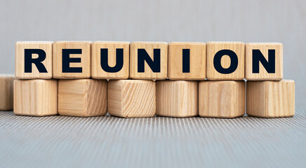 REUNION - word on wooden cubes on a beautiful gray background