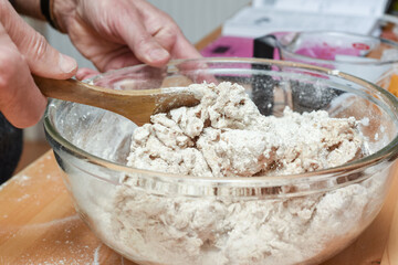 Person making bread in home kitchen adding ingredients to make the dough