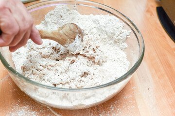 Person making bread in home kitchen adding ingredients to make the dough