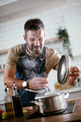 Happy smiling man preparing tasty meal. Young man cooking in the kitchen.
