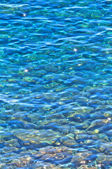 Overhead view of blue and green water surface abstract in a sea - Underwater pebbles