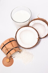 opened coconut near coconut flakes in wooden bowl and glass of coconut milk isolated on white background. tropical, nut. coco.