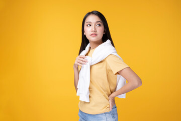 Happy Asian woman wearing yellow t-shirt and white sweater on shoulder with yellow background. Young Asian woman over yellow background. Portrait of happy Asian female .