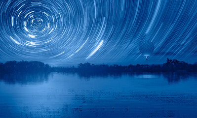 Long exposure photo of night sky star trail over the  lake at sunset