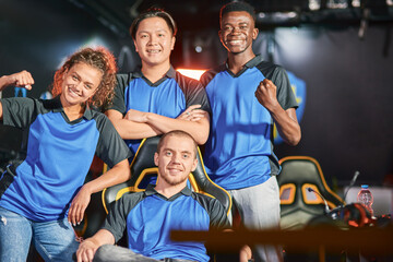 Celebrating success. Happy multiracial cybersport team smiling at camera and gesturing after eSport...