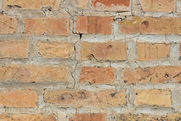 Symmetrical brick wall background. Red and brown colored terracotta bricks from an abandoned house, some clean, some dirty. Cracks in the wall.
