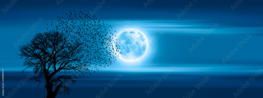 Poster silhouette of birds flying over rising blue moon with lone dead tree 