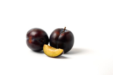 Whole and sliced black cherry plums in white background