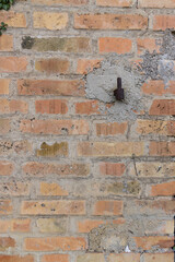 Symmetrical brick wall background. Red and brown colored terracotta bricks from an abandoned house, some clean, some dirty. Cracks in the wall.