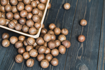 macadamia nuts in a wooden bowl close up on a dark background