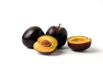 Fototapeta premium Whole and sliced black cherry plums on the white table
