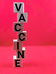 Wooden block alphabet "VACCINE" isolated with red background. Medical concept.