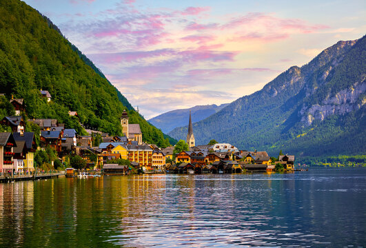 Hallstatt, Austria. Lake Hallstattersee with calm blue water among austrian Alps mountains. Embankment of antique picturesque town. View to old houses on coast and chapel of church.