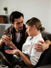 Young woman sick in bed. .Woman drinking medicine, having stomach pain. Husband comforts his wife..