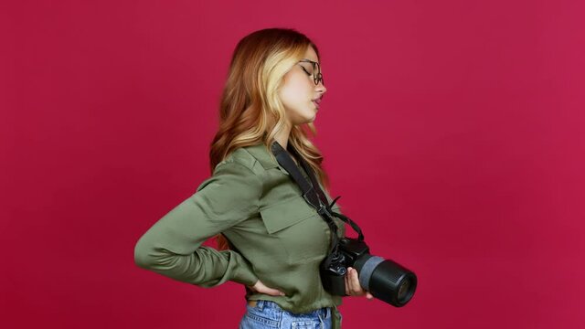 Young blonde girl photographer suffering from pain in shoulder for having made an effort over isolated background
