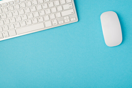 Top view photo of desktop with white keyboard and mouse on isolated blue background with blank space