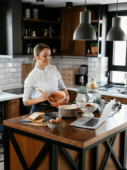 Young woman in kitchen. Beautiful woman following recipe and cooking..