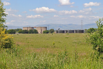 Fototapeta na wymiar Country Landscape with Hills Blue Sky & Industrial Storage Tanks 