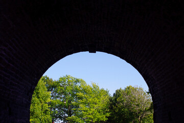 Fototapeta na wymiar old curved tunnel entrance looking out at trees with copy space