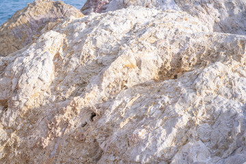 Huge white stone with sunlight near the sea. White stone surface or background. Rocky landscape.