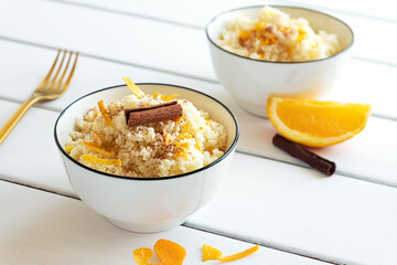 Delicious homemade couscous with oranges and cinnamon on rustic wooden background. Tasty vegan food.