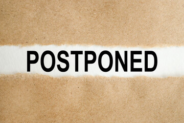 Postponed. text on white paper over torn paper background.