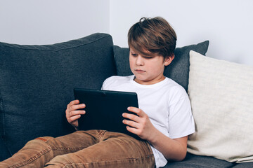 Portrait of diligent boy using his laptop while doing homework. Distance or home education, personal education and self isolation concept. Selective focus